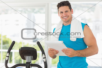 Smiling trainer with clipboard in gym