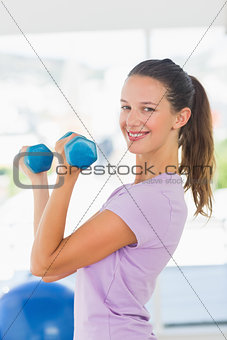 Side view of a smiling woman lifting dumbbell weights