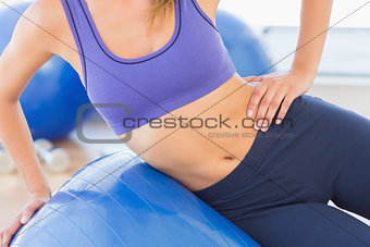 Mid section of a fit woman exercising with fitness ball