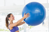 Smiling fit young woman holding fitness ball