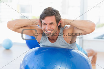 Happy fit man stretching on exercise ball