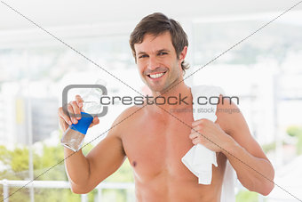 Shirtless young man with towel drinking water