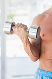 Mid section of a sporty young man with dumbbell