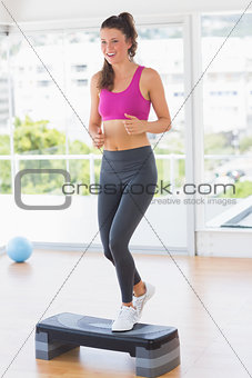 Full length of a fit woman performing step aerobics exercise