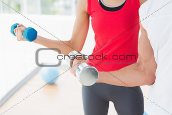 Mid section of a sporty couple with dumbbells