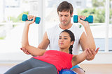 Instructor assisting woman with dumbbell weights