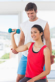 Instructor assisting woman with dumbbell weight