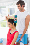 Instructor assisting woman with dumbbell weight
