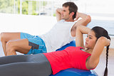 Fit couple exercising on fitness balls in gym