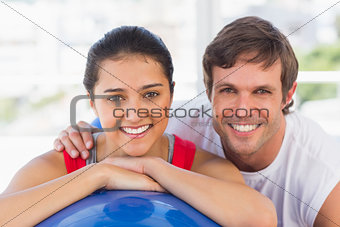 Smiling fit couple with exercise ball at gym