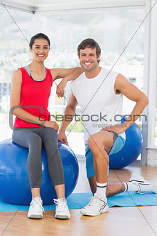 Portrait of a smiling fit couple with exercise ball at gym