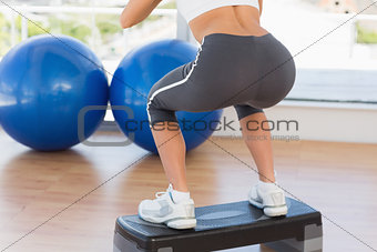 Low section rear view of a fit woman exercising on step