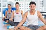 People in meditation pose with eyes closed at fitness studio