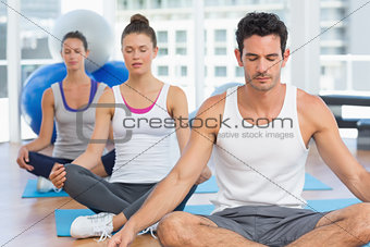 People in meditation pose with eyes closed at fitness studio
