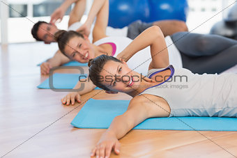 Smiling people doing pilate exercises in fitness studio