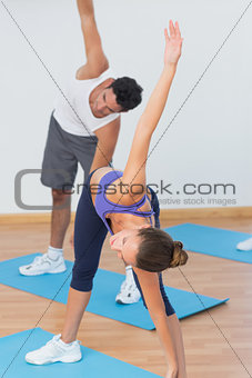 Sporty couple stretching hands at yoga class