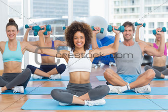 Portrait of a fit class lifting dumbbell weights