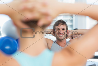 Smiling male with blurred people doing stretching exercises