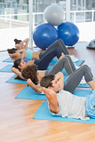 Determined people doing sit ups in fitness studio