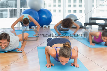 Determined people doing push ups in fitness studio