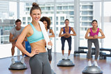 Smiling woman with fit people performing step aerobics exercise