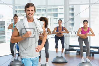 Man with fit people performing step aerobics exercise