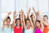 Fit people gesturing thumbs up in exercise room