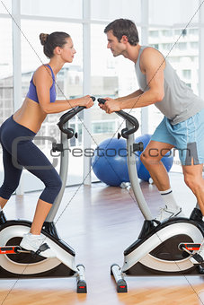 Side view of a couple working at spinning class in gym