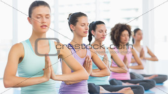 Young sporty women with joined hands sitting in row