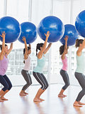 Fit women holding blue fitness balls in exercise room
