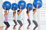 Fit women holding blue fitness balls in exercise room