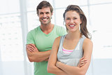 Fit young couple with arms crossed in exercise room