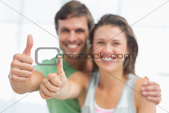 Portrait of a fit young couple gesturing thumbs up