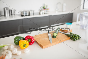 Vegetables with knife and chopping board on kitchen counter