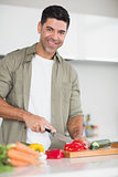 Smiling man chopping vegetables in kitchen