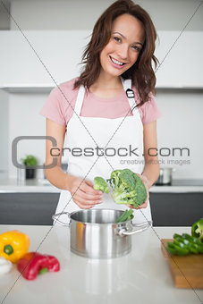 Smiling young woman with broccoli in kitchen