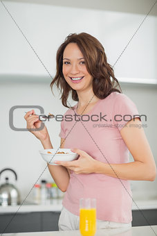 Smiling woman with a bowl of cereals in kitchen