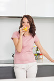Smiling woman drinking orange juice in kitchen