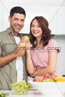Portrait of a smiling couple with fruits in kitchen