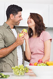 Couple with fruits looking at each other in kitchen