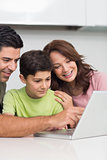 Smiling couple with son using laptop