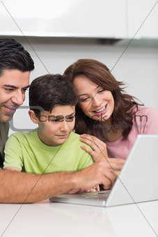 Smiling couple with son using laptop