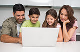 Smiling couple with kids using laptop
