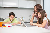 Mother with kids using laptop in kitchen
