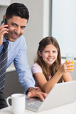 Smiling father with daughter using laptop in kitchen
