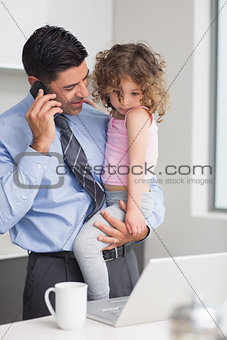 Well dressed father using cellphone while carrying his daughter
