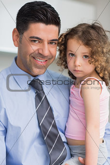 Smiling well dressed father carrying his daughter