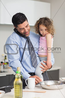 Well dressed father with daughter preparing food while on call