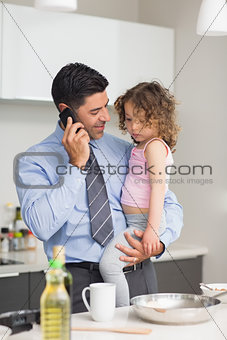 Well dressed father with daughter preparing food while on call