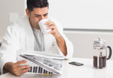 Man drinking coffee while reading newspaper in kitchen
